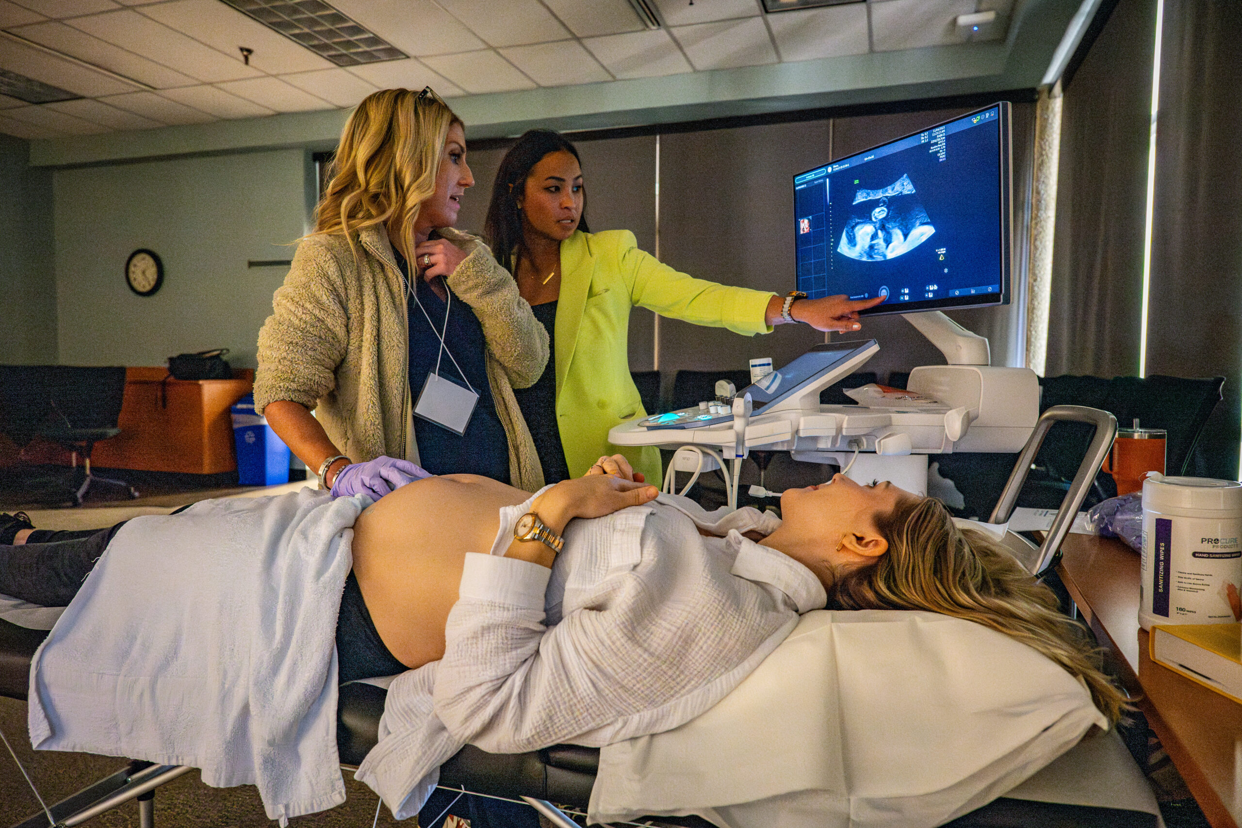 Two clinicians looking at an ultrasound with a pregnant woman.